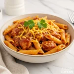A high-angle photo of a generous serving of BBQ Chicken Pasta in a matte off-white bowl, garnished with fresh cilantro.