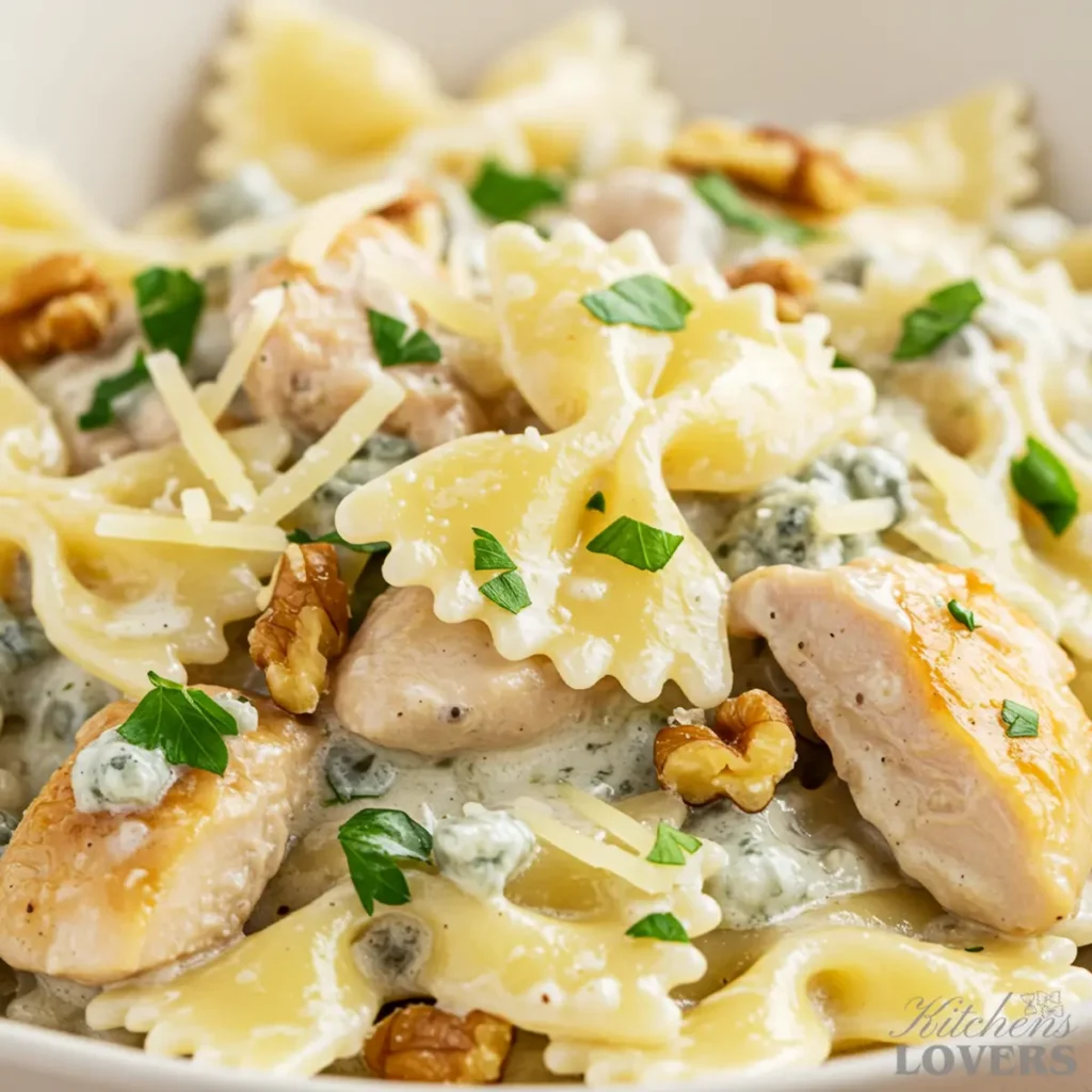 An extreme close-up of chicken gorgonzola pasta, showcasing the detailed textures of the creamy sauce, farfalle noodles, chicken, parsley, and walnuts.