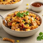 A vibrant 75-degree high-angle photo of BBQ Chicken Pasta Salad with rotini, chicken, corn, beans, cheese, and cilantro.