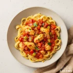 A top-down photo of a hearty Chicken Cacciatore Pasta Recipe in a ceramic bowl, garnished with fresh herbs.