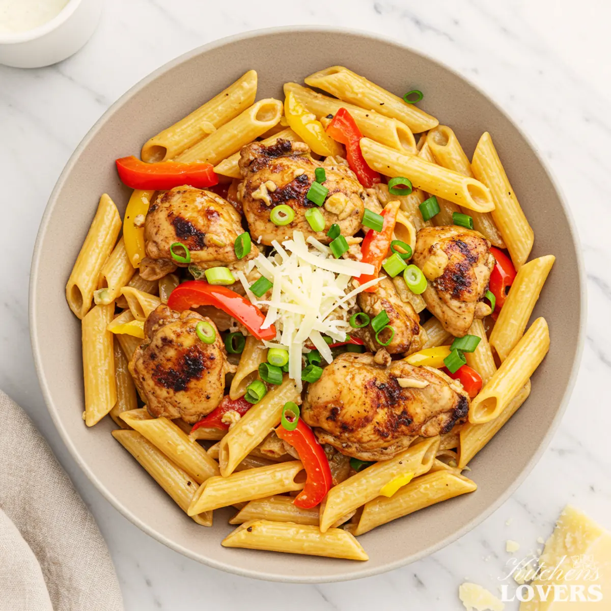 A top-down photo of creamy Jerk Chicken Pasta in a bowl, garnished with green onions and Parmesan cheese.