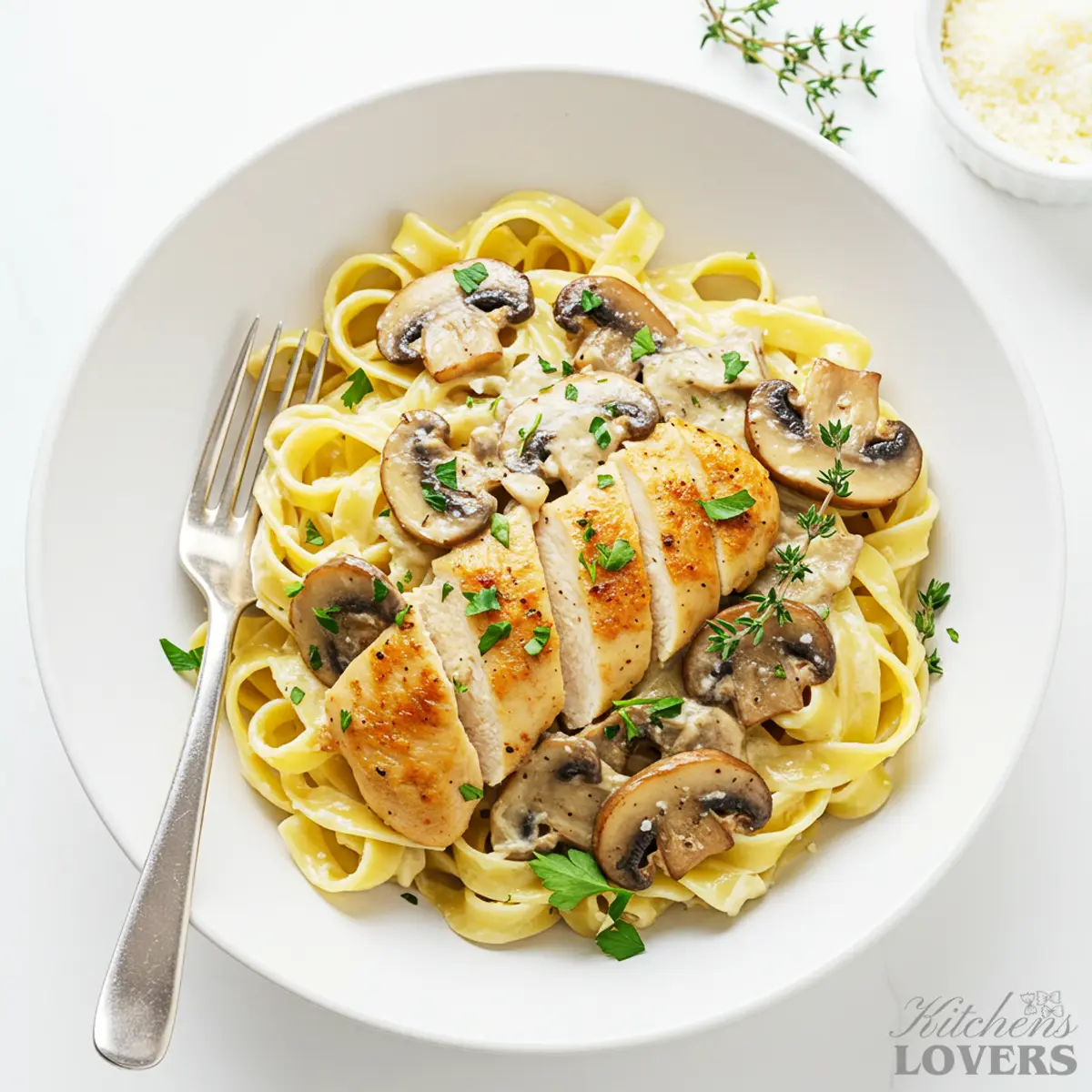 An overhead shot of a white bowl filled with creamy chicken marsala pasta, garnished with fresh parsley.